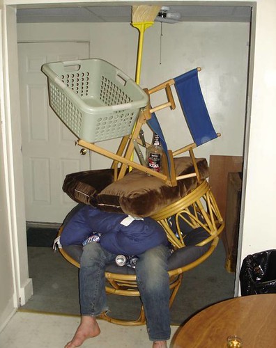 drunk guy passed out on papason chair with things piled on top of him like chairs and cushions and laundry basket